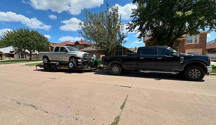 Car loading and hauling service with black pickup and trailer Loading a car onto a trailer being hauled by a black pickup truck