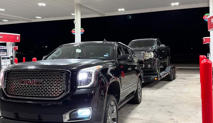 Car hauling service with trailer for vehicle transport Car hauling another black car on a trailer at a gas station